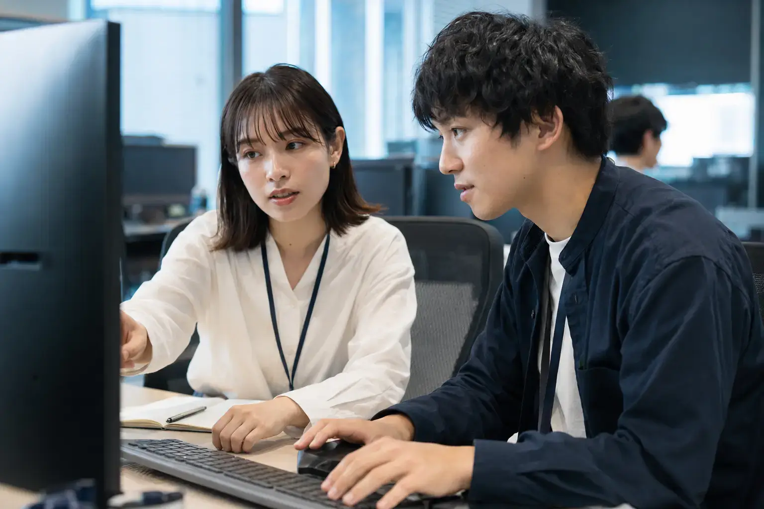 Two developers pair-programming at a workstation